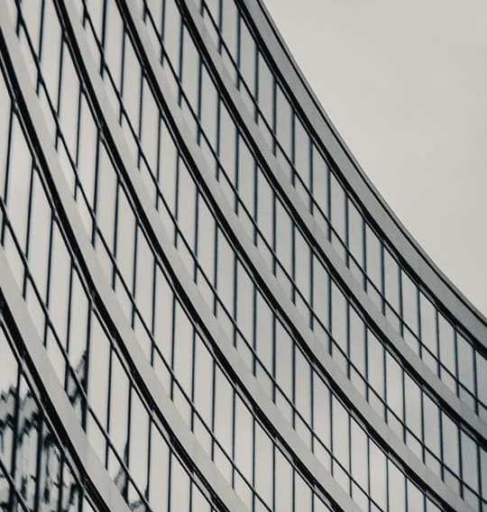 Black and white image of a modern building featuring a sleek, curved glass facade, showcasing architectural elegance.